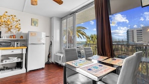 A modern kitchen with a refrigerator, microwave, and coffee maker, a dining area with a table and chairs, and a balcony with a view of palm trees and buildings. - Waterside, Studio #21, Family Friendly, Close to Beach (Clearwater Beach)