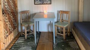 Une pièce chaleureuse avec une table en bois, deux chaises, un tableau encadré, une bougie allumée et une grande paire de bois de cerf accrochée au mur.