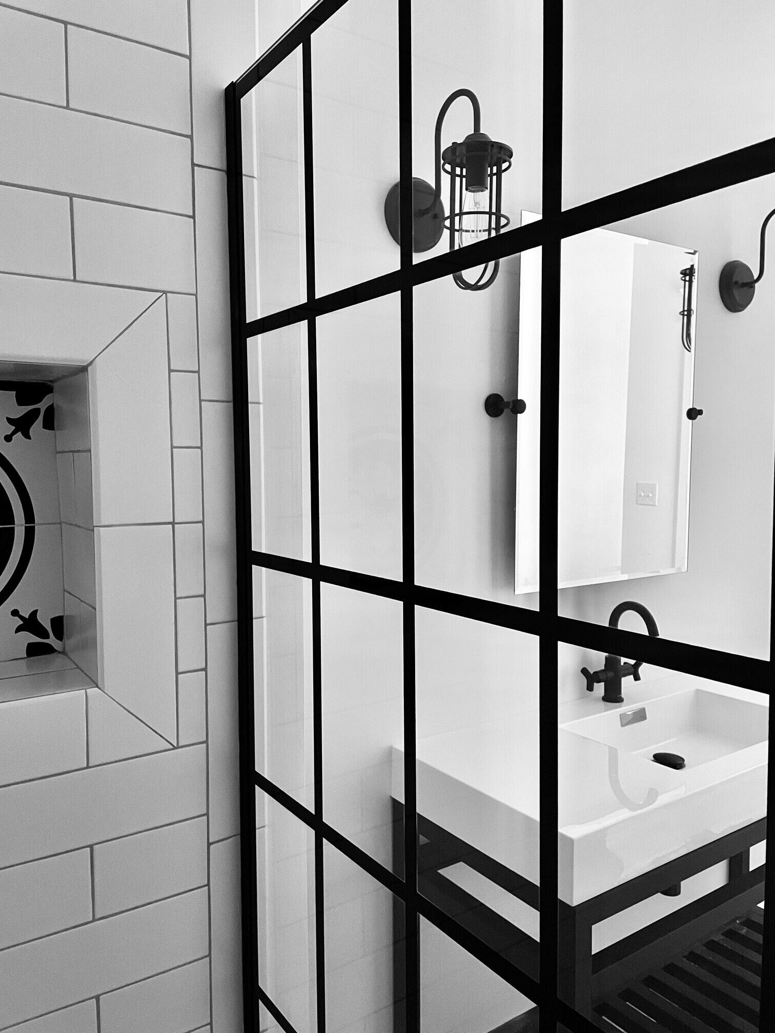 A bathroom with a white sink, black fixtures, and a mirror.