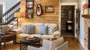 Un salon chaleureux avec un canapé, des fauteuils à rayures, une table basse et une cheminée.