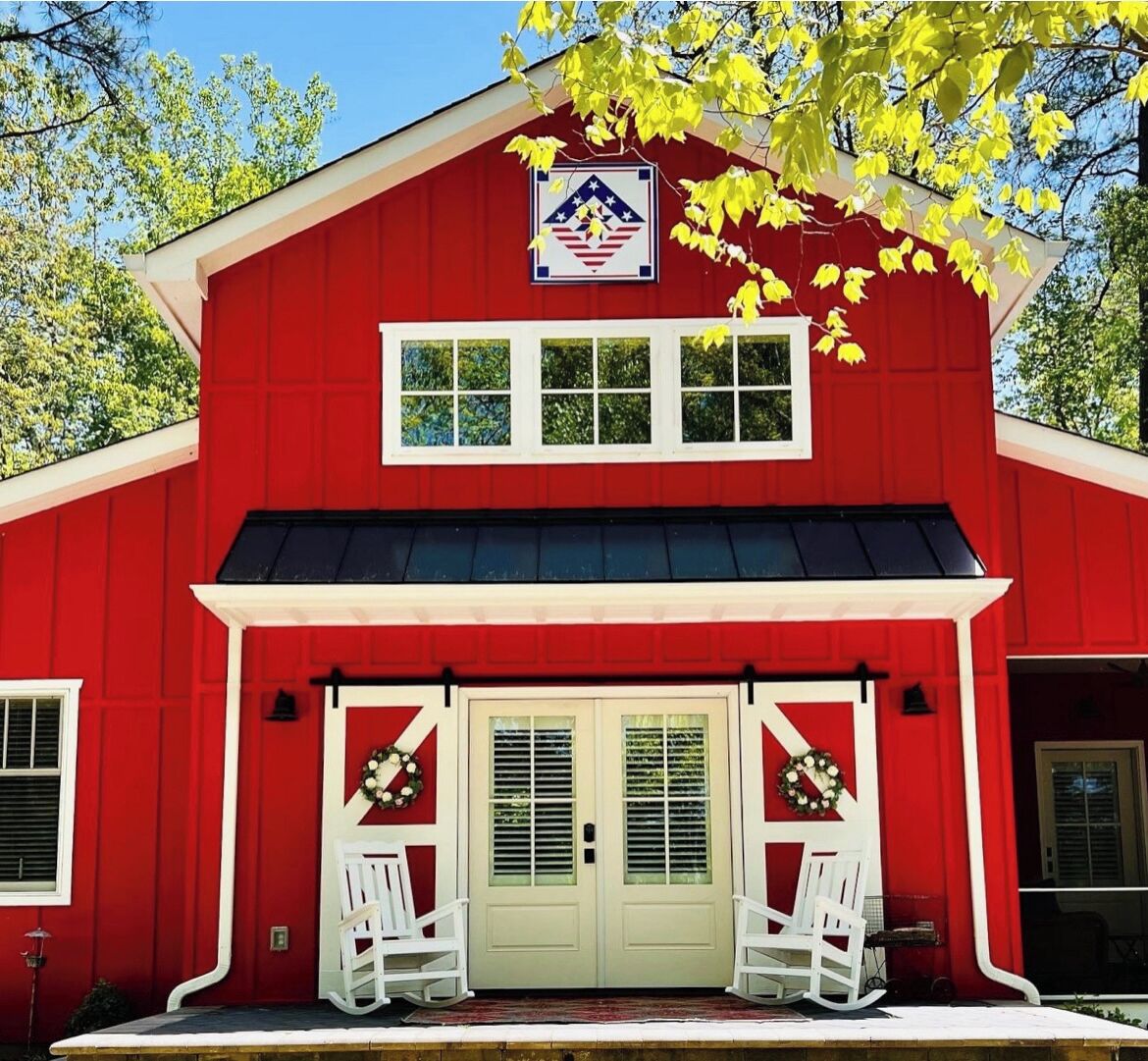 A red building with a white door and two white chairs in front.