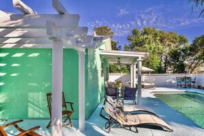 Un área de piscina con sillas de descanso y una pérgola.