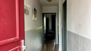 A hallway with a red door, wooden flooring, and a ceiling light fixture. - Alpilles-side apartment with terrace in Saint-Remy-de-Provence (Saint-Rémy-de-Provence)