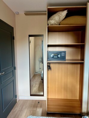 A room with a wooden wardrobe, a mirror, and a fan.