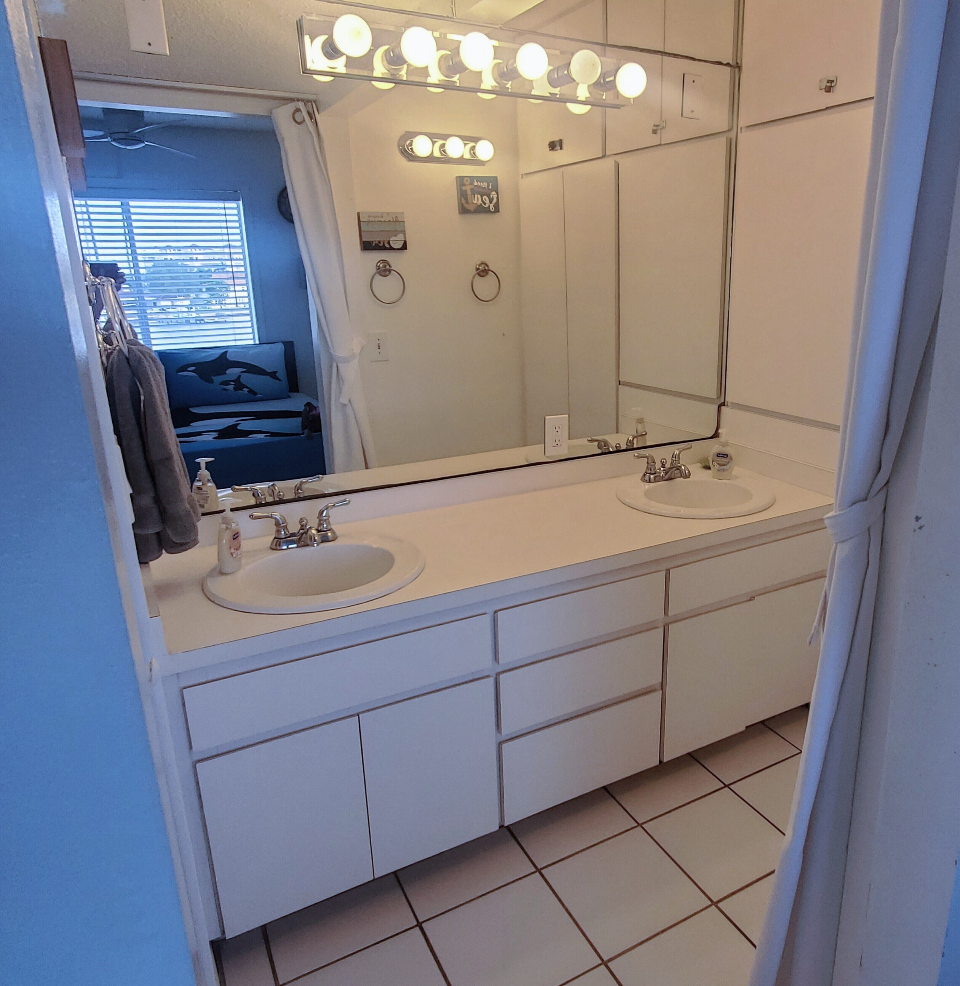 A bathroom with two sinks, a large mirror, and overhead lights.