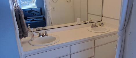 A bathroom with two sinks, a large mirror, and overhead lights.