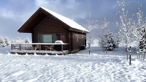 A wooden cabin with a snow-covered roof and a porch. - River Haven Cabin-South-Private River Access! (Emigrant)