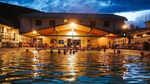 A swimming pool area with a covered seating area and a building in the background. - River Haven Cabin-South-Private River Access! (Emigrant)