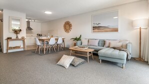Un salon moderne avec un canapé gris, une table basse et un coin repas comprenant des chaises et une table.