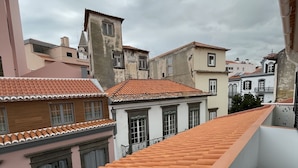 A balcony with a tiled roof overlooking a residential area with various buildings. - Downtown Cosy and Quiet Apartment (Funchal)