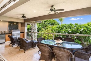 A covered outdoor dining area with wicker furniture, a glass table, and a view of lush greenery. - Luxurious Ho'olei 12-2, Lush View, Close to Pool, Sleeps 8 in beds, Central AC! (Kihei)