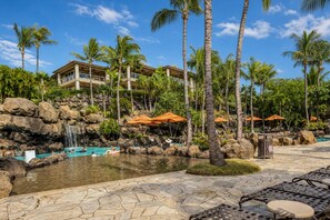 A resort with a pool area, palm trees, and a building with balconies.