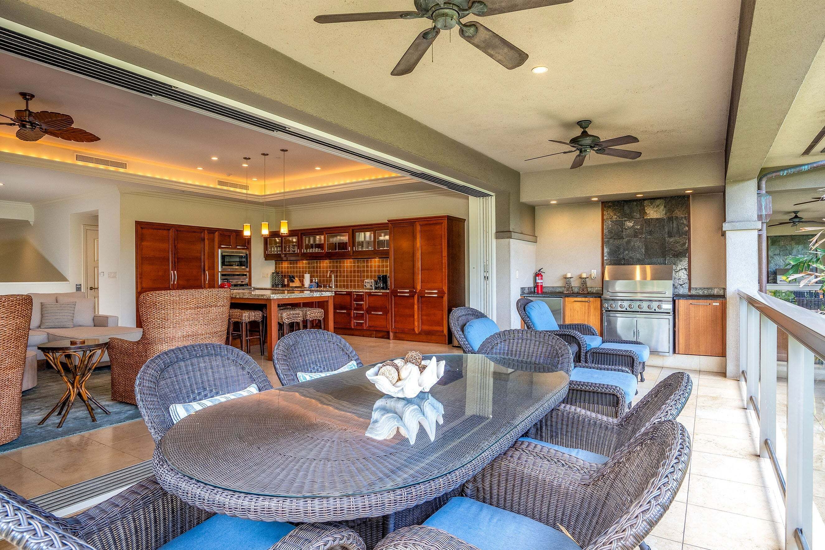 A spacious kitchen with modern appliances, a dining area with wicker furniture, and a balcony with a view.
