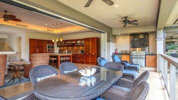 A spacious kitchen with modern appliances, a dining area with wicker furniture, and a balcony with a view.