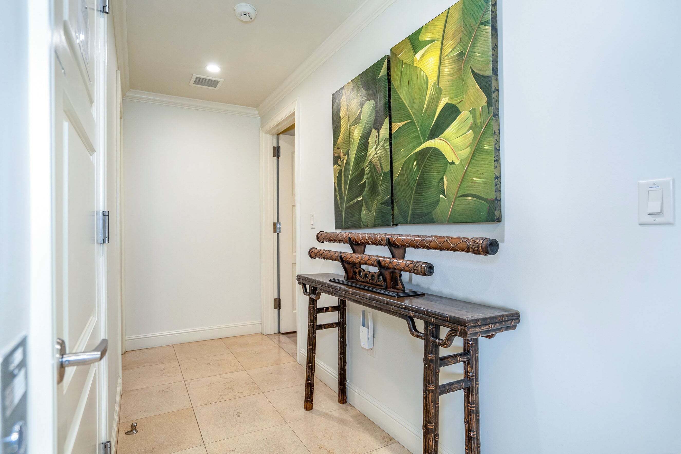 A hallway with a wooden console table and a large botanical painting on the wall.
