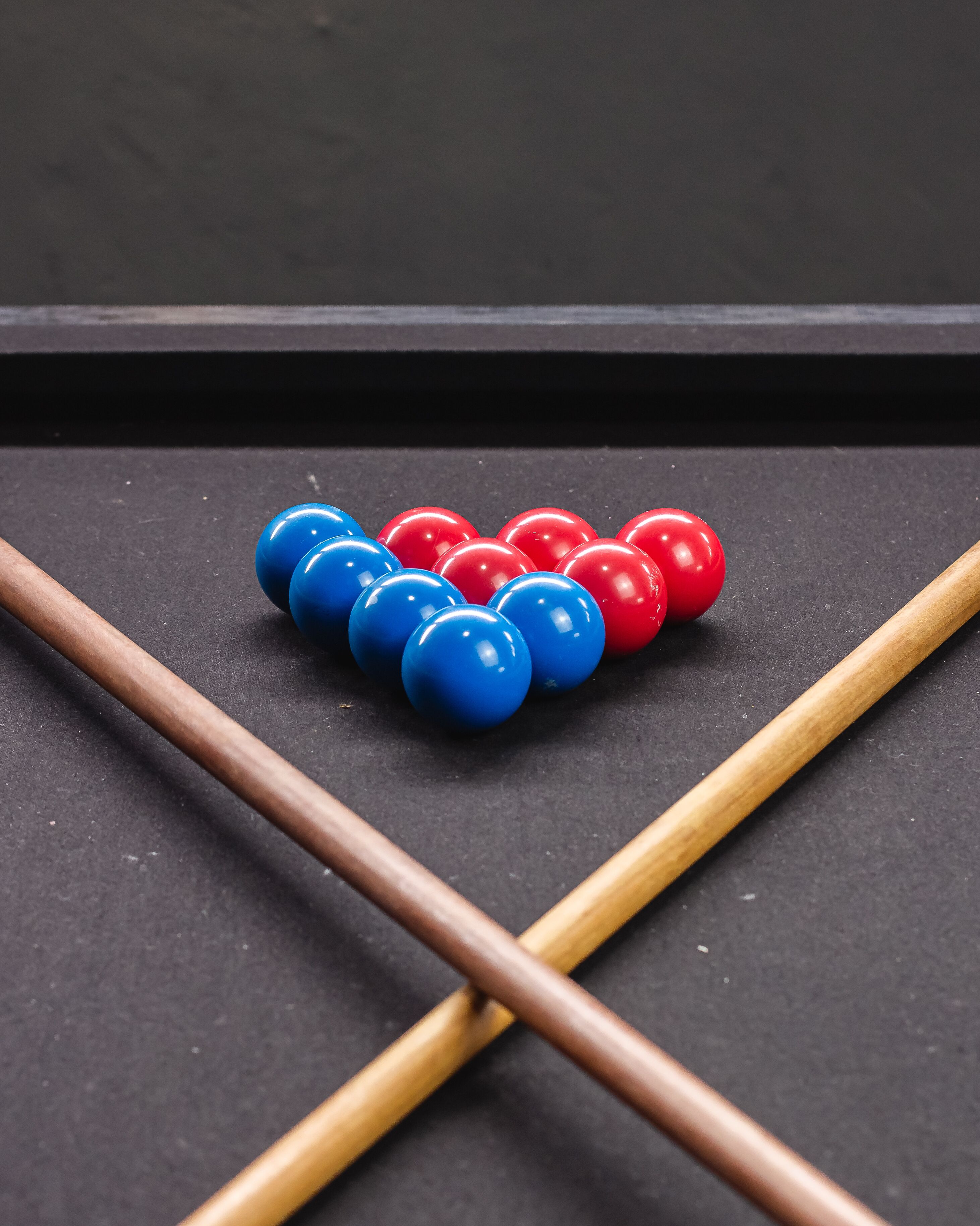 A pool table with a set of billiard balls and two wooden sticks.