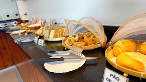 Un bufé con diversas opciones de comida, como pan, bollería y frutas.