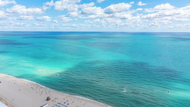 Een strand met helder turquoise water en een zandstrand.