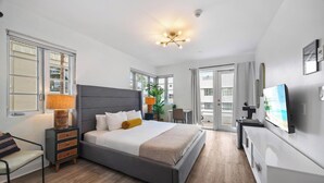 Een moderne hotelkamer met een groot bed, nachtkastjes, een televisie en een balkon.