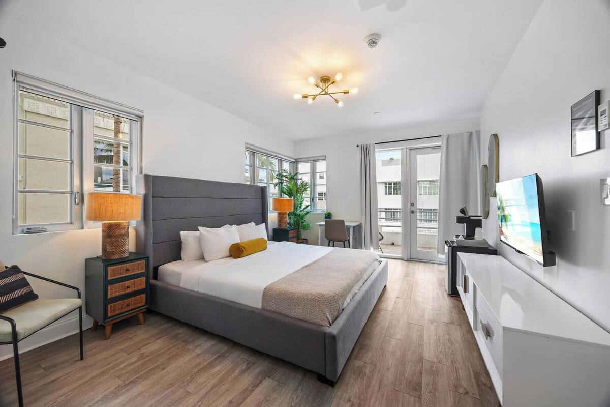 Une chambre d’hôtel moderne avec un grand lit, des tables de chevet, une télévision et un balcon.