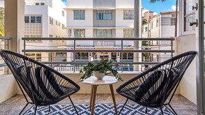 Een balkon met twee zwarte wickerstoelen en een klein tafeltje met een bloempot. Het uitzicht omvat een gebouw met een bord waarop 'Chesterfield' staat.