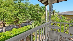 Un balcon agrémenté de fauteuils en osier, un espace abrité et une végétation luxuriante.