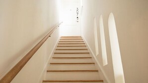 Un escalier avec des marches en bois et des murs blancs, menant à une porte portant le numéro 307.