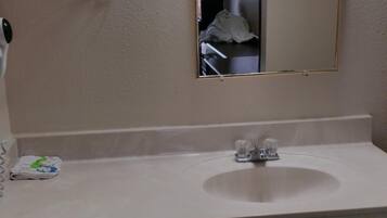 A bathroom with a white sink, a mirror, and a towel dispenser.