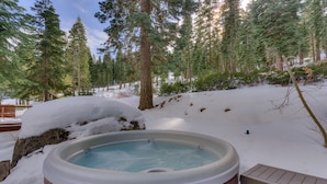 A hot tub surrounded by snow-covered ground and tall evergreen trees. - Home Run at Northstar - TLUXP (Truckee)