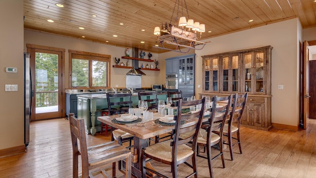 A spacious kitchen with wooden cabinets, a dining area with a wooden table and chairs, and a large window providing natural light. - Home Run at Northstar - TLUXP (Truckee)