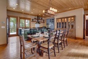 A spacious kitchen with wooden cabinets, a dining area with a wooden table and chairs, and a large window providing natural light. - Home Run at Northstar - TLUXP (Truckee)