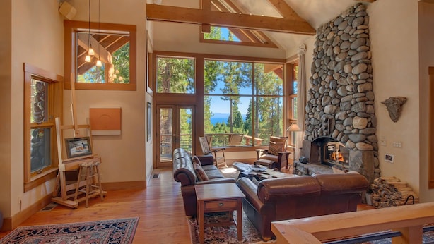 Un salón amplio con chimenea de piedra, ventanas grandes y una zona de estar acogedora.