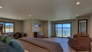 Una camera da letto con un letto grande, una scrivania, una sedia e vista sull'acqua tramite una porta scorrevole.