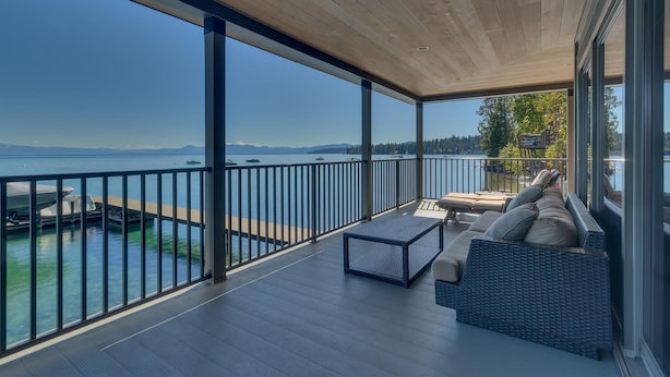 Un ampio balcone con vista sul mare, soffitto in legno e un'area salotto con cuscini.
