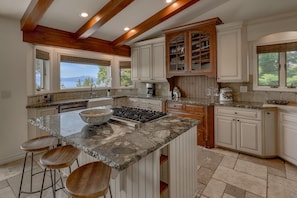 A spacious kitchen with a large island, wooden cabinets, and a view of the outdoors.