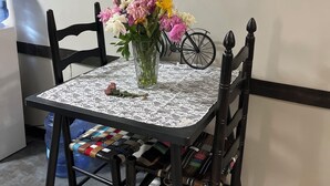A dining table with a lace tablecloth, surrounded by black chairs, and a vase with flowers. - Glamping at Peace In The Valley (Glasgow)