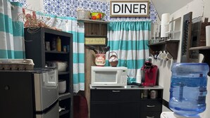 A compact kitchenette with a microwave, water dispenser, and a sign indicating a dining area. - Glamping at Peace In The Valley (Glasgow)