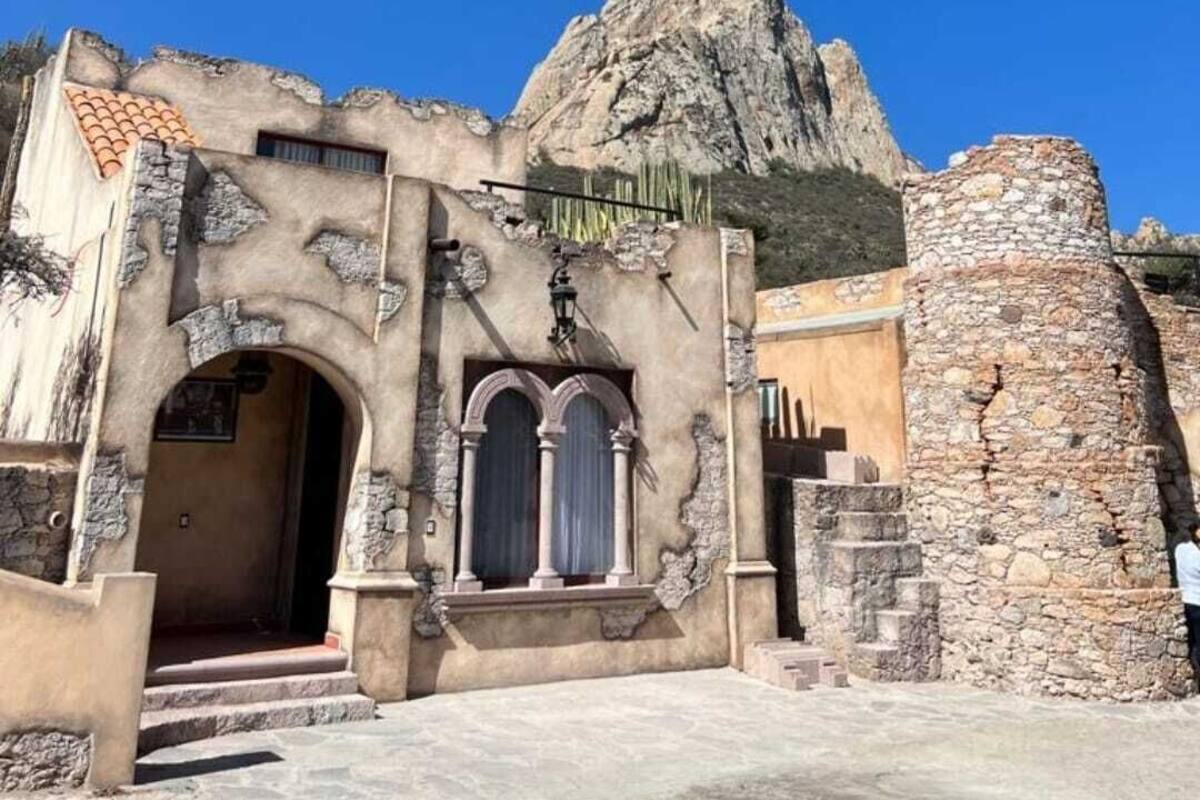 A historic building with a stone facade, an arched entrance, and a staircase leading to the door.