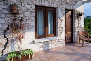 A stone building with a wooden door and window, a bench, and potted plants. - Hotel Centenario Los Arroyitos (Ezequiel Montes)