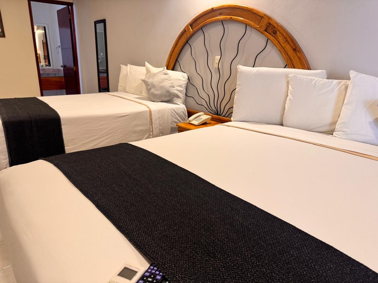 Habitación de hotel con dos camas, cabecera de madera y teléfono junto a la cama.