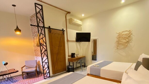 A hotel room with two beds, a desk, a chair, a TV, and an air conditioning unit. - Gran Plaza Hotel Centro Historico (Iguala de la Independencia)