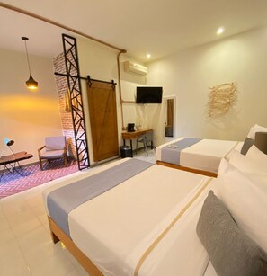Habitación de hotel con dos camas, un escritorio, una silla, un televisor y un equipo de aire acondicionado.