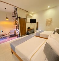 Habitación de hotel con dos camas, un escritorio, una silla, un televisor y un equipo de aire acondicionado.