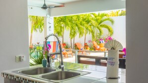 A kitchen with two stainless steel sinks, a ceiling fan, and a view of a patio with chairs and plants.