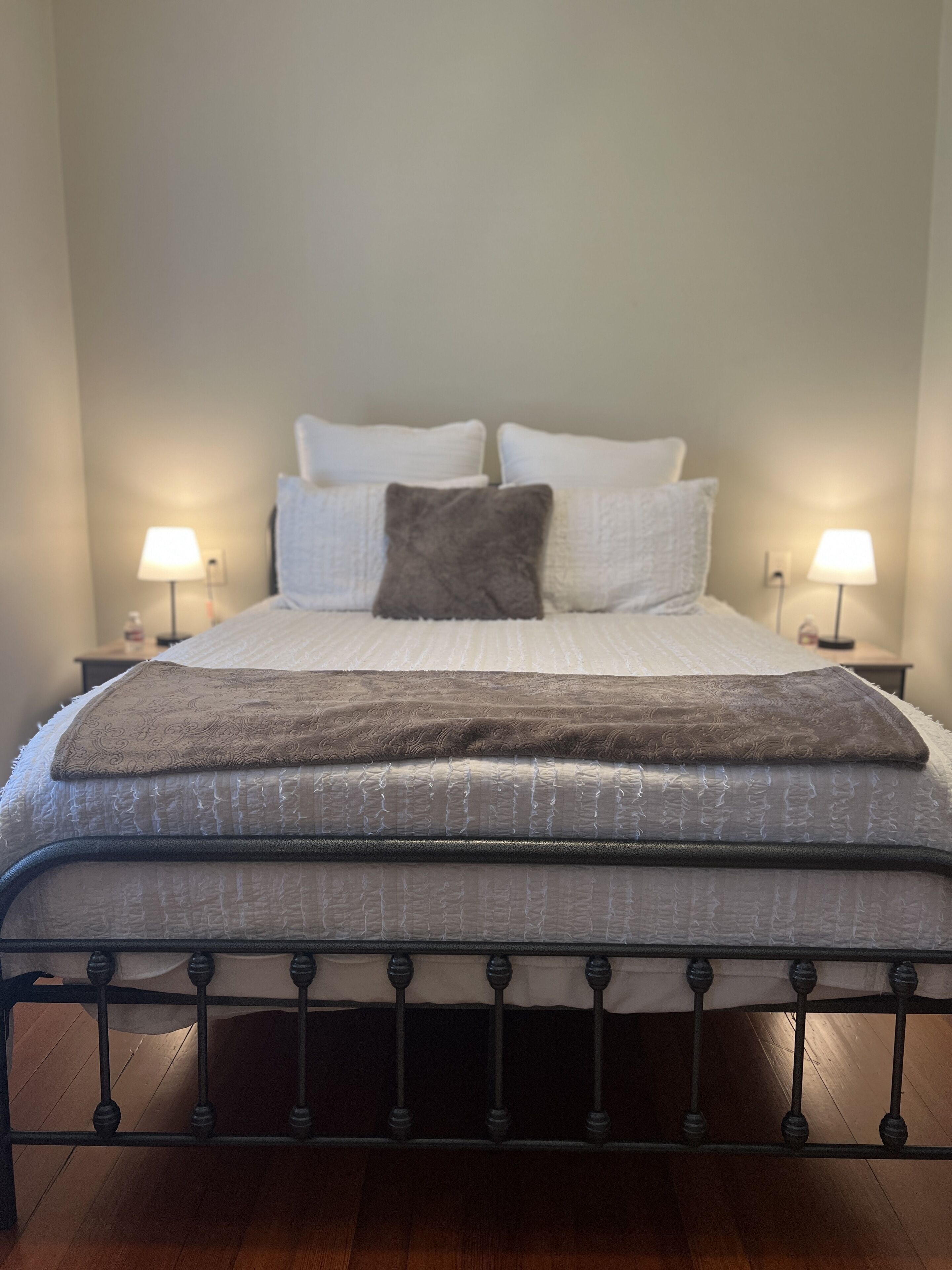 A bed with a metal frame, white bedding, and two bedside lamps.