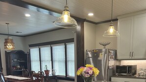 Una cocina moderna con una isla central, electrodomésticos de acero inoxidable, armarios de madera e iluminación colgante.