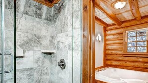 A bathroom with a shower, a bathtub, and a window.