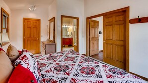 A bedroom with a bed, a dresser, a mirror, and two wooden doors.