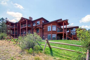 A large, multi-story wooden building with balconies and large windows, surrounded by a grassy area and a wooden fence. - Black Canyon Inn Unit F2 (Estes Park)