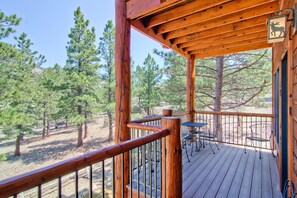 A wooden deck with a railing, a table with chairs, and a deer sign.